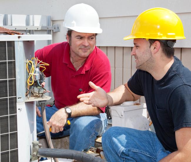 image of two AC repair men fixing an air conditioner